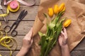 Woman florist making tulips bouquet on wooden table Royalty Free Stock Photo