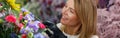 Smiling woman flower shop owner in apron looking on bouquet of flowers at florist store Royalty Free Stock Photo