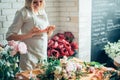 Woman florist taking pictures of flowers with mobile phone