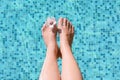 Woman with flower holding feet over water in swimming pool, closeup Royalty Free Stock Photo