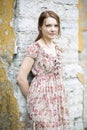 Woman in flowered dress rests on wall