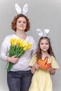 A woman with flowers and a girl with bunny ears and a basket of Easter eggs. The family celebrates Easter. Royalty Free Stock Photo