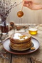 Woman flowing maple syrup on stack of traditional pancakes