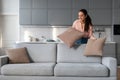 Woman fluffing cushions on a sofa in a neat, stylish room Royalty Free Stock Photo