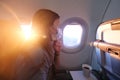 Woman Flying on an Airplane Wearing a Face Mask and Looking in Windo