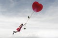 woman flying free in the sky hanging from a red flower