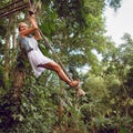 Woman flying high on rope swing on wild jungle background Royalty Free Stock Photo