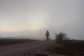 Woman fog road travel. Mystical creepy autumn landscape with gray fog