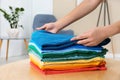 Woman folding bright clothes on table indoors.