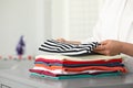 Woman folding clothes at grey table indoors, closeup