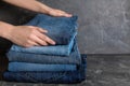 Woman folding stylish jeans on grey table. Space for text