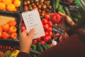 woman follows shopping list when buying fruits and vegetables in supermarket. Royalty Free Stock Photo