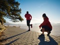 Woman folowing running man at lake beach. Team of runners