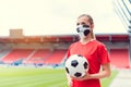 Woman football player wearing face mask in empty stadium