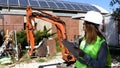 Woman foreman at building site wearing work helmet and reflecting jacket use the tablet.