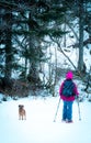 woman in the forest hiking with snowshoes and backpack. with her adorable dog looking at the camera Royalty Free Stock Photo