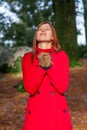 Woman on a forest praying and enjoying the warmth of the winter sunlight