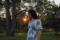 Woman alone in the forest at sunset with sunburst shining through trees