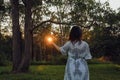 Woman alone in the forest at sunset with sunburst shining through trees