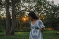 Woman in the forest at sunset with sunburst shining through the trees