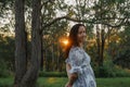 Woman in the forest at sunset with sunburst shining through the trees