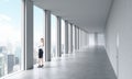 A woman in formal clothes is looking out the window. Empty modern bright clean interior of an open space office. Huge panoramic wi Royalty Free Stock Photo