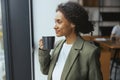 A woman in formal wear sips coffee, gazes out window Royalty Free Stock Photo