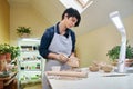 woman forming leaf shaped clay by hands, closeup in artistic studio