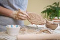 woman forming leaf shaped clay by hands, closeup in artistic studio