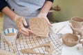 woman forming leaf shaped clay by hands, closeup in artistic studio