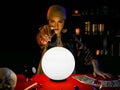 Woman fortune teller using crystal ball on red table to forecast future