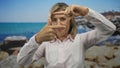 Woman framing with hand in studio with seaside backdrop using gesture to simulate viewfinder; creativity vision inspiration Royalty Free Stock Photo