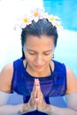 Woman with frangipani flowers in her hair, praying pose in swimming pool Royalty Free Stock Photo