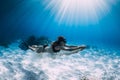 Woman free diver glides with white sand over sandy sea. Freediving underwater in Hawaii