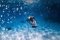 Woman freediver glides with fins over sandy sea bottom and bubbles Royalty Free Stock Photo