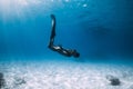 Woman freediver glides with fins over sandy sea bottom. Freediving and sun light in ocean Royalty Free Stock Photo