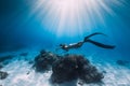 Woman freediver glides with fins over sandy sea bottom. Freediving and sun light in ocean Royalty Free Stock Photo