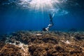 Woman freediver glides over reef bottom with fins and turtle Royalty Free Stock Photo