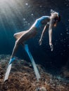 Woman freediver glides underwater in blue sea. Freediving with girl in deep ocean and sun rays