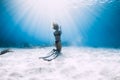 Woman freediver posing with fins over sandy sea. Freediving underwater