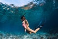 Woman freediver swim in pink swimsuit underwater with fins. Freediving underwater in ocean