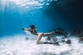 Woman freediver swim underwater over sandy bottom with sand