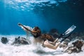 Woman freediver swim underwater over sandy bottom with sand