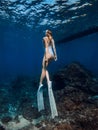 Woman freediver with fins underwater. Freediving with attractive girl in deep blue ocean