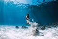 Woman freediver with white sand glides over sandy sea with fins. Freediving underwater