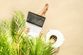Woman freelancer with laptop sitting under coconut palm tree  branches. Female eating royal dates fruit from a bowl. Summer sand Royalty Free Stock Photo