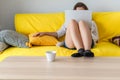 Woman freelancer sitting on the couch with laptops in the socks and putting legs on the table. Work at home. Concept. Cup coffee. Royalty Free Stock Photo