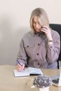 woman freelancer speaking to client by phone and making notes in a notebook. vertical shot of blond working woman Royalty Free Stock Photo