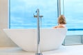 woman in freestanding white bath. Modern bathroom interior design. Beauty, healthy lifestyle concept Royalty Free Stock Photo
