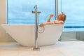 woman in freestanding white bath. Modern bathroom interior design. Beauty, healthy lifestyle concept Royalty Free Stock Photo